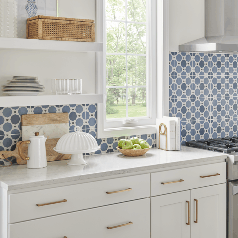 Kitchen with white cabinets, gold pulls and a blue pattern back splash